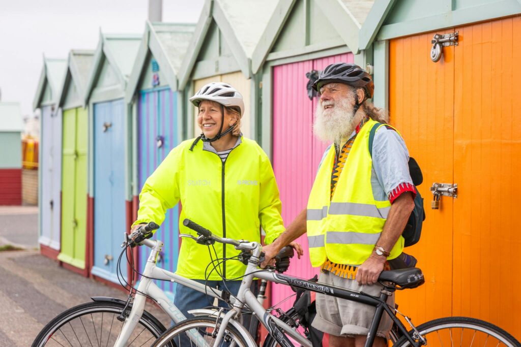 Elderly Couple with Bicycles Near the Beach Huts