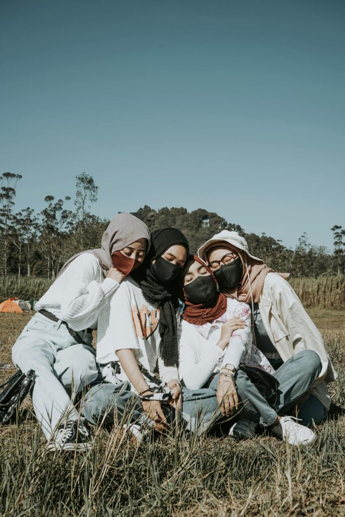 Friends Sitting Together on a Grass Field