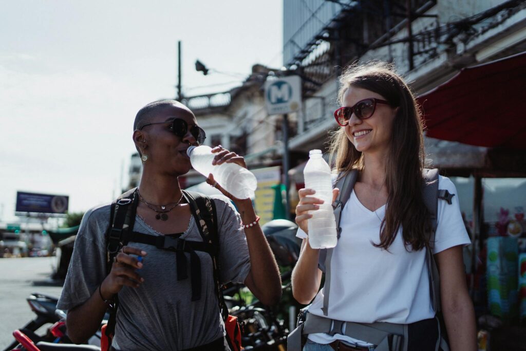 Women Drinking Water while Walking on the Street